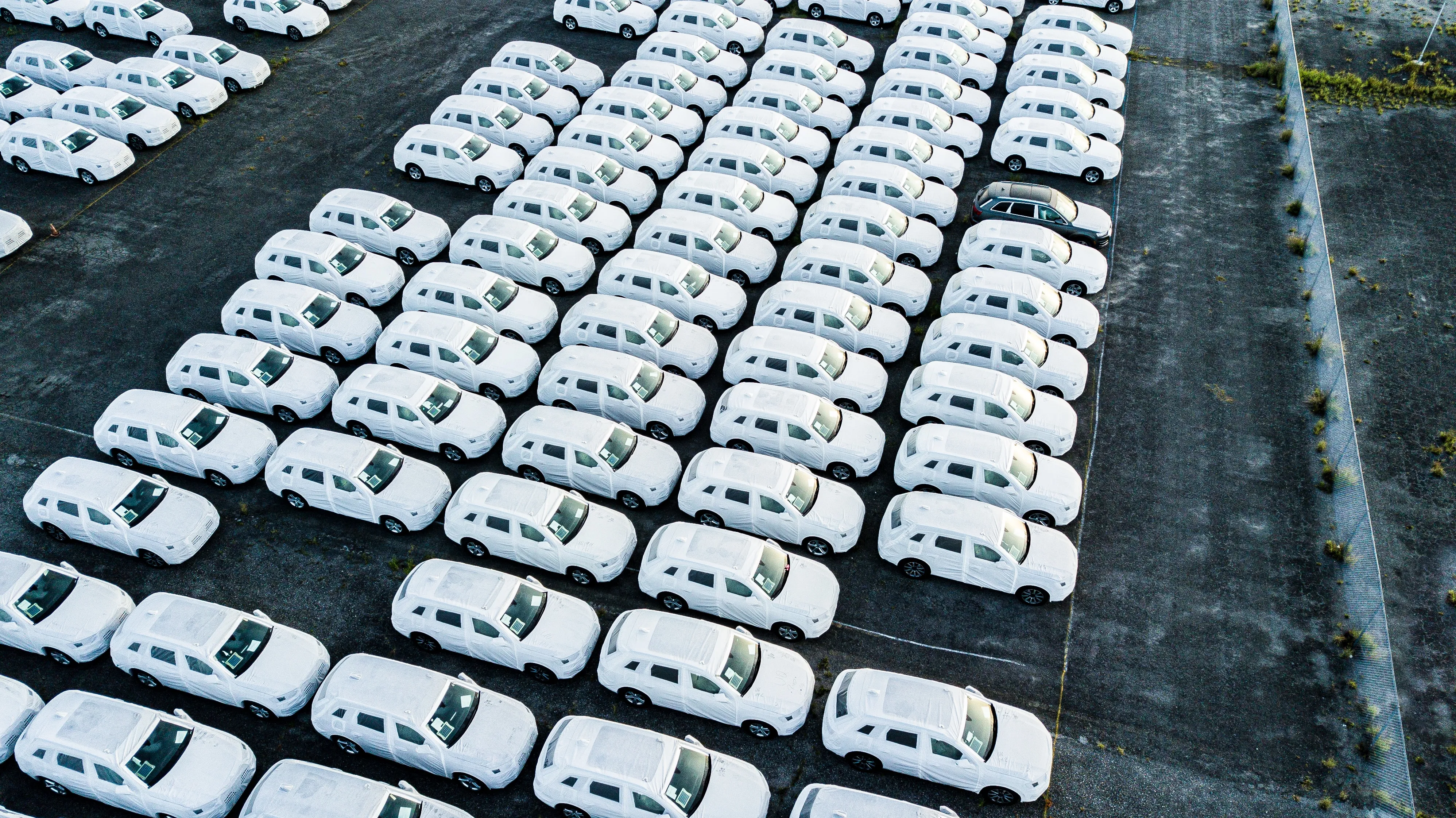 Rows of shrink-wrapped vehicles parked in a Jack Cooper storage yard