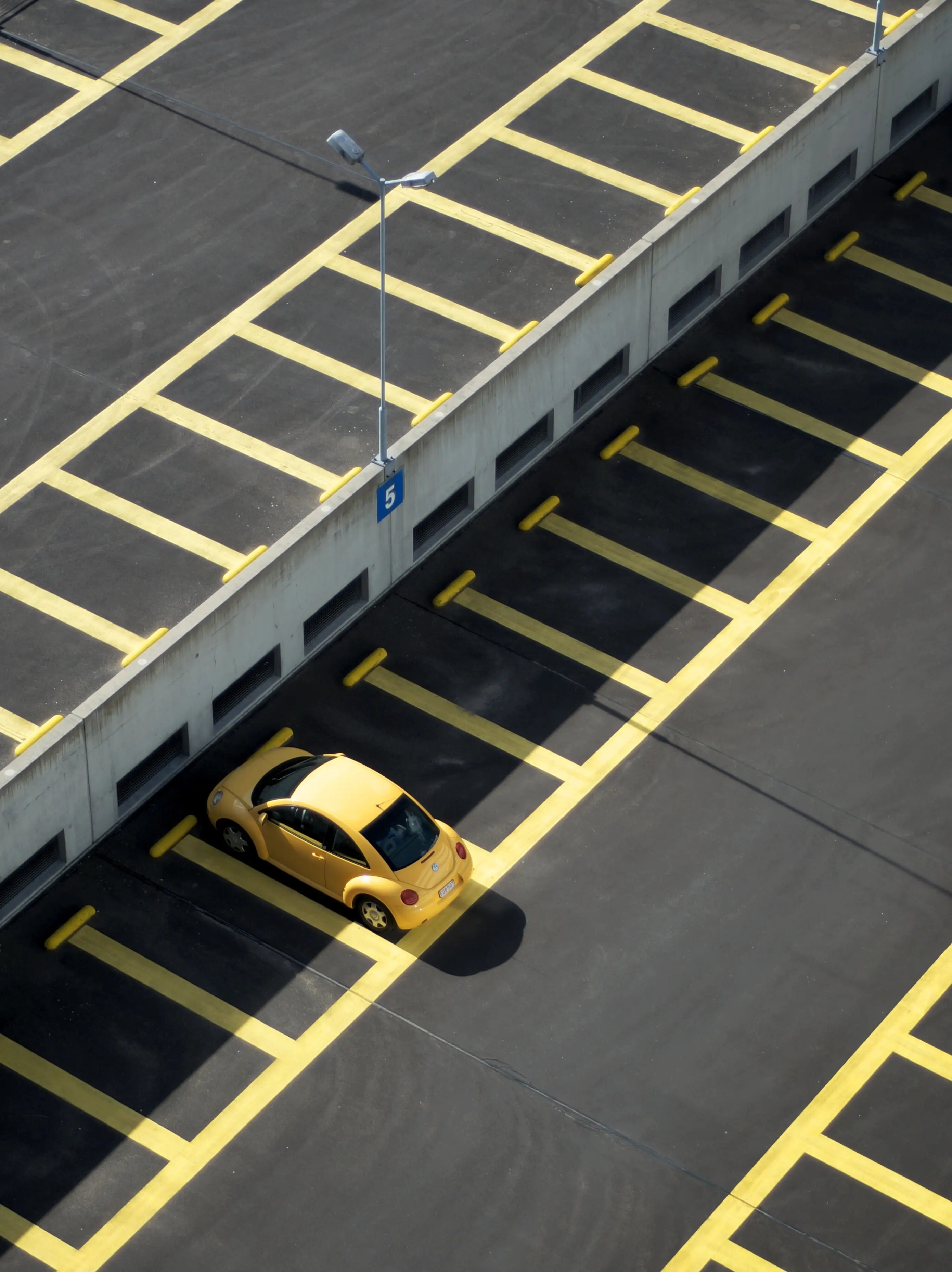 A single yellow car parked in an otherwise empty parking deck