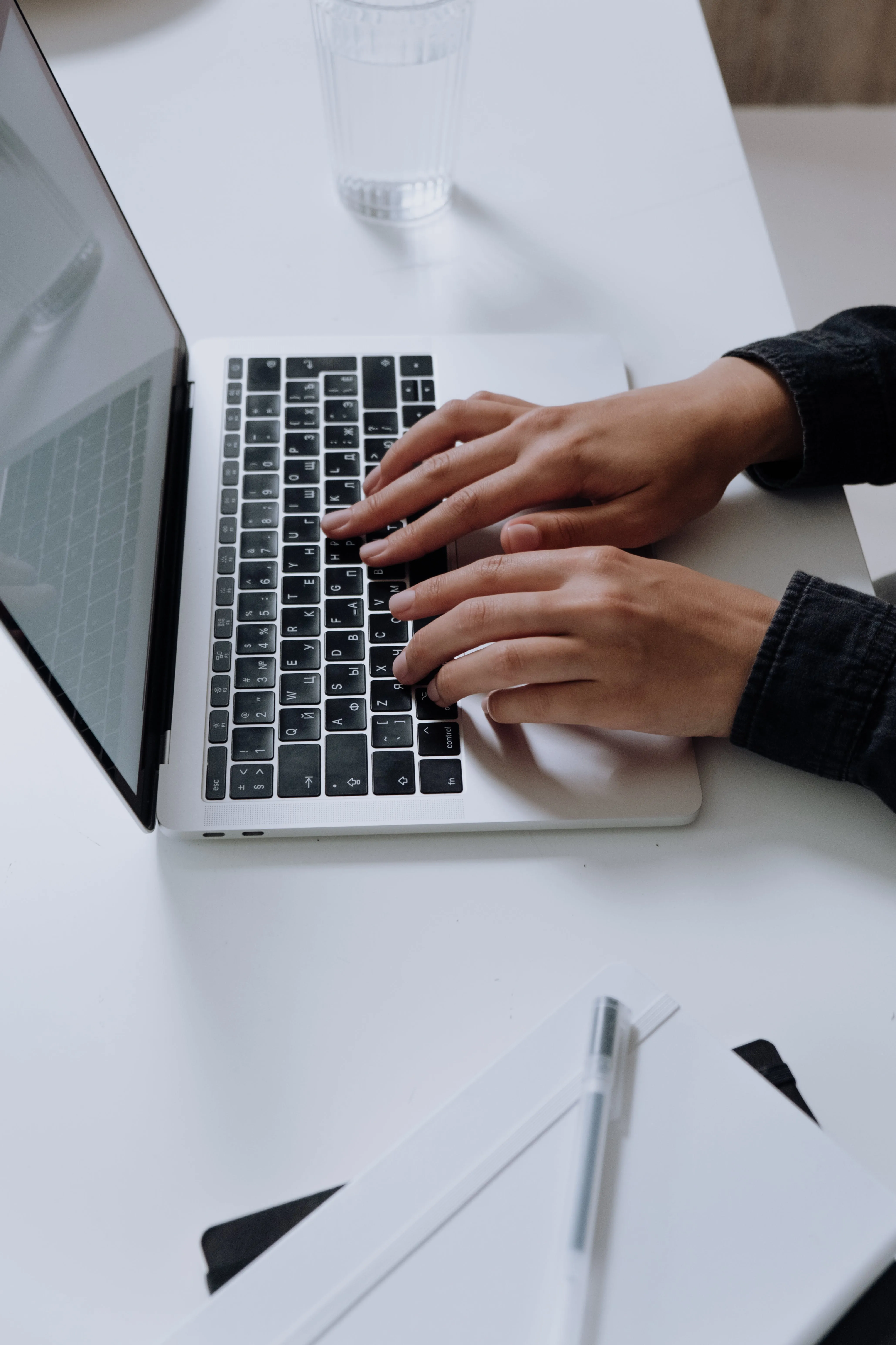 Hands typing on a laptop at a desk